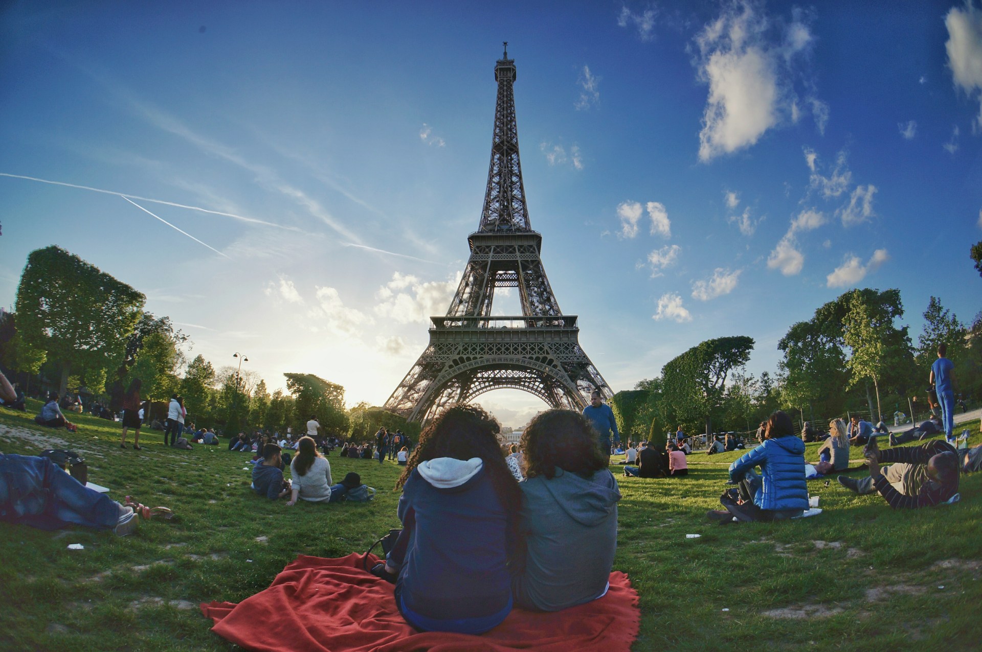 Jovens a descontrair na relva do Campo de Marte, com a Torre Eiffel ao fundo